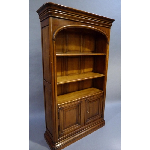 286 - A Cherrywood open bookcase cabinet having a moulded pediment, arched freeze above open shelves with ... 