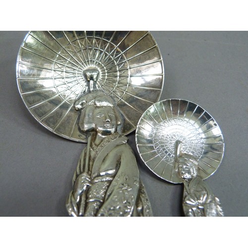 230 - A Sterling silver spoon in the form of a bijin carrying a parasol; together with another of similar ... 