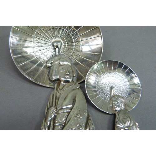 230 - A Sterling silver spoon in the form of a bijin carrying a parasol; together with another of similar ... 