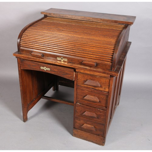 292 - An oak tambour fronted desk with fitted interior above a pedestal of four drawers flanked by a singl... 