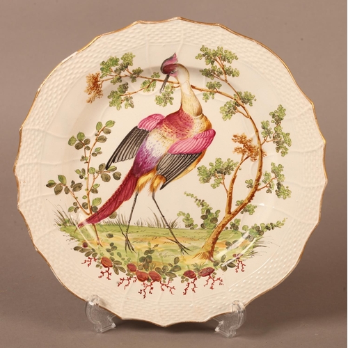 10 - A Creamware plate painted in the style of Chelsea with an exotic bird and tree in polychrome enamels... 