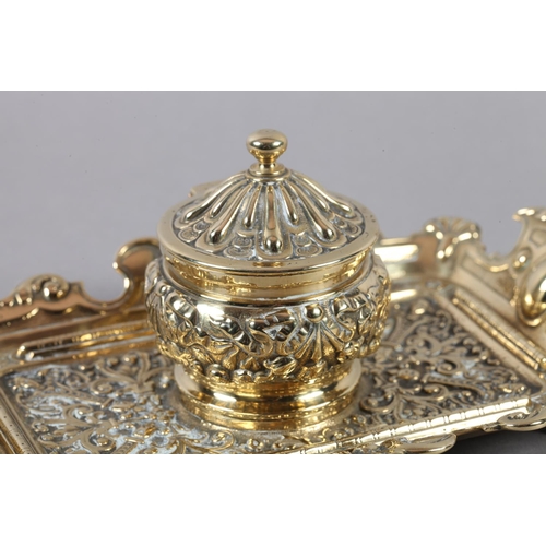 14 - A Victorian brass desk standish fitted with a central inkwell and cover cast with ribboned harebells... 