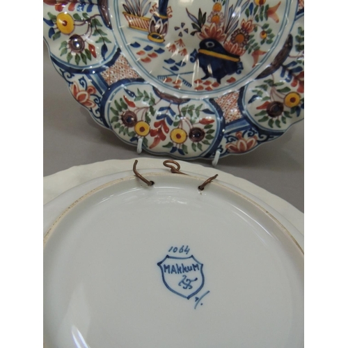 31 - Two Makkum faience dishes, circular with fluted rims, the first painted with urns of flowers to the ... 