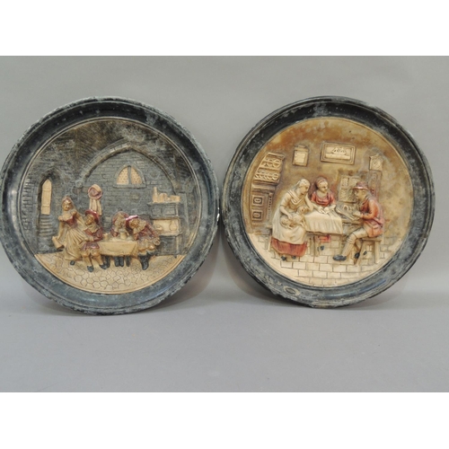 33 - A pair of pottery wall plaques, moulded in relief with figures in a tavern and figures around a kitc... 