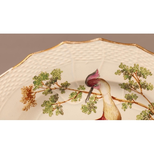 10 - A Creamware plate painted in the style of Chelsea with an exotic bird and tree in polychrome enamels... 