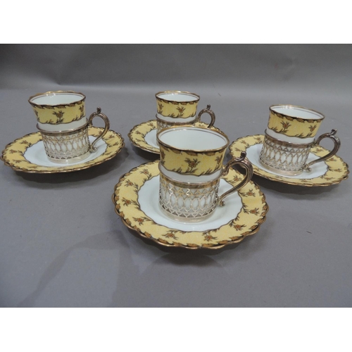 12 - A set of four Aynsley porcelain coffee cans and saucers, the cans set within pierced silver cylindri... 