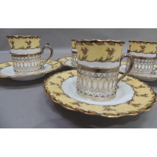 12 - A set of four Aynsley porcelain coffee cans and saucers, the cans set within pierced silver cylindri... 