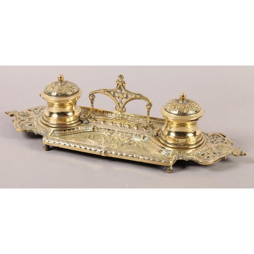 13 - A Victorian brass double desk standish fitted with two glass lined inkwells, pierced handle and oppo... 