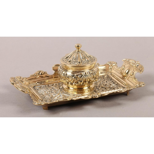 14 - A Victorian brass desk standish fitted with a central inkwell and cover cast with ribboned harebells... 