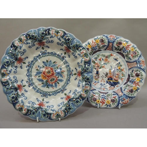 31 - Two Makkum faience dishes, circular with fluted rims, the first painted with urns of flowers to the ... 