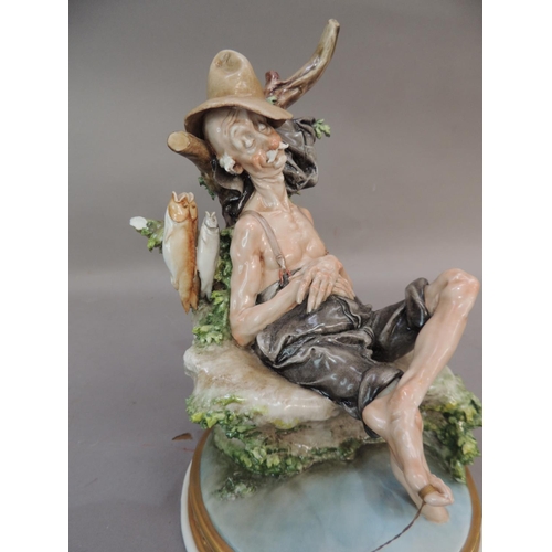 37 - A Naples porcelain figure of an elderly sleeping fisherman seated on the banks of a stream, 25cm hig... 