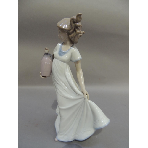 52 - A Nao porcelain figure of a young girl carrying a two handled vase under her arm with a bird perched... 