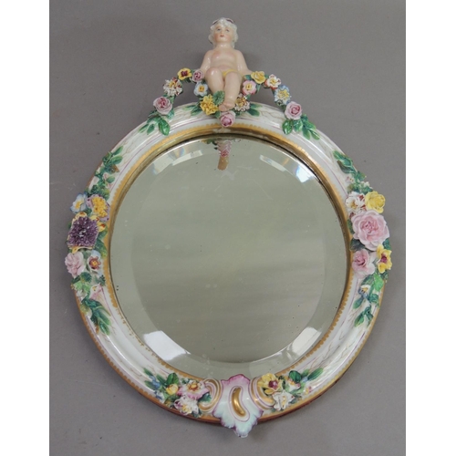 55 - A Continental porcelain floral encrusted oval mirror, the bevel plate within a frame set to the top ... 