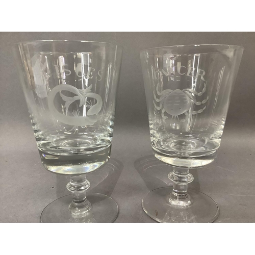 13 - A pair of glass goblets, etched with a crab the horoscope sign Cancer and a fish for Pisces, on a bl... 