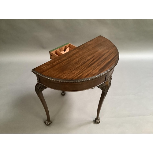 725 - A mahogany card table in George III style, the D-shaped top above a deep frieze on acanthus carved c... 