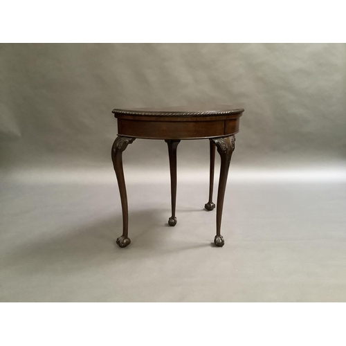 725 - A mahogany card table in George III style, the D-shaped top above a deep frieze on acanthus carved c... 