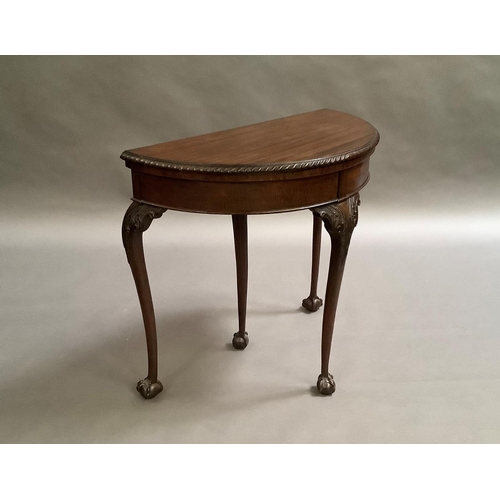 725 - A mahogany card table in George III style, the D-shaped top above a deep frieze on acanthus carved c... 