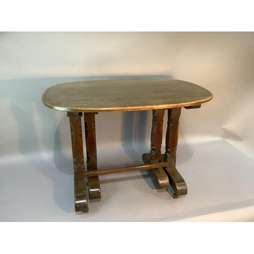 104 - An oak occasional table, the oval top above chamfered carved square legs on trestle bases: together ... 