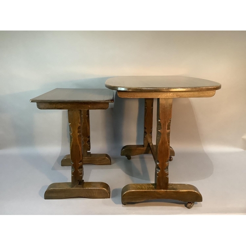 104 - An oak occasional table, the oval top above chamfered carved square legs on trestle bases: together ... 