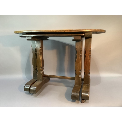 104 - An oak occasional table, the oval top above chamfered carved square legs on trestle bases: together ... 