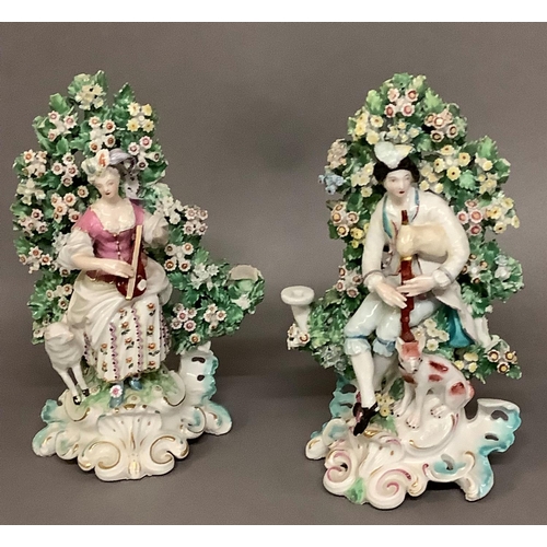 33 - A pair of Derby porcelain seated bocage figures of a piper and hound and shepherdess with lamb, appr... 