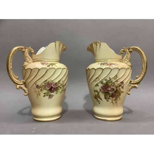 43 - A pair of Royal Worcester blush ivory ewers having a wrythern fluted and moulded lip and shouldered ... 