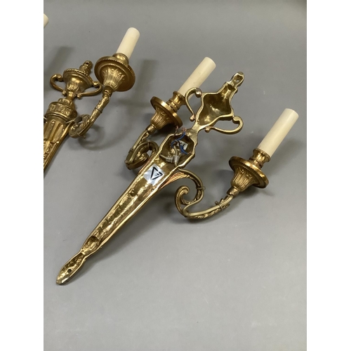 52 - A pair of gilt metal twin light wall sconces of classical design, two handled urn finial and leaf ca... 