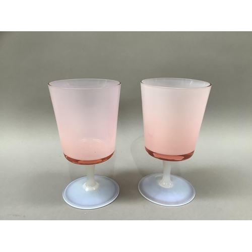 7 - A pair of pink tinted and opalescent glass goblets with bucket bowls and slender stem on a circular ... 