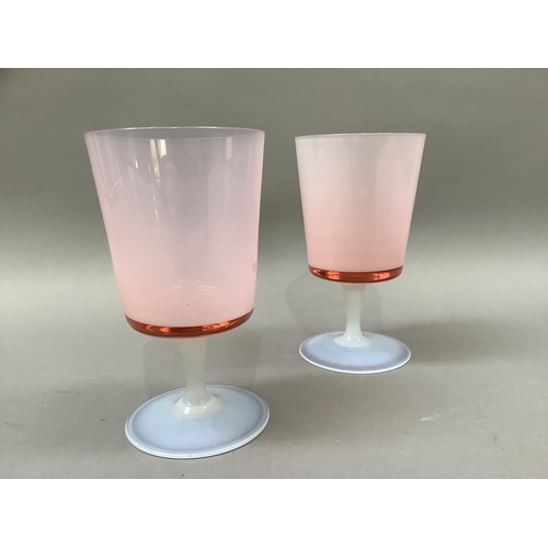 7 - A pair of pink tinted and opalescent glass goblets with bucket bowls and slender stem on a circular ... 