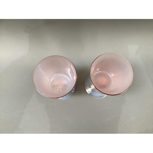 7 - A pair of pink tinted and opalescent glass goblets with bucket bowls and slender stem on a circular ... 