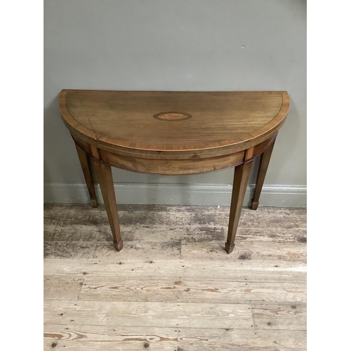 362 - A 19th century mahogany and cross banded demi lune card table inlaid with a shell paterae, on square... 