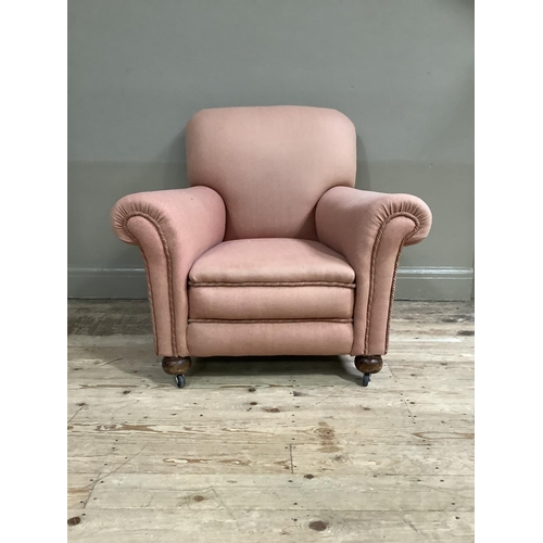 368 - An upholstered armchair in pale coral on compressed bun feet and later casters, circa 1920's