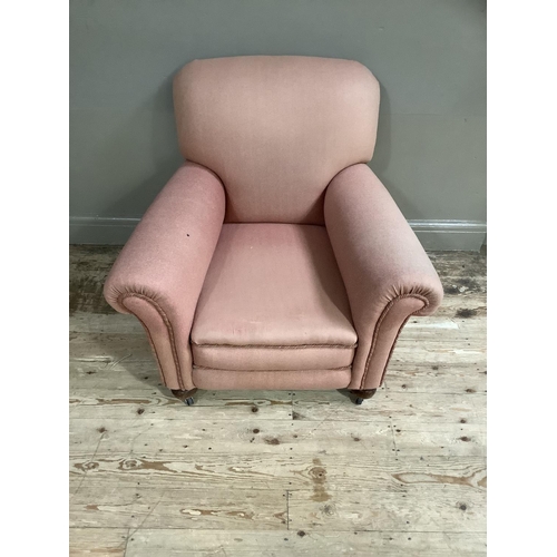 368 - An upholstered armchair in pale coral on compressed bun feet and later casters, circa 1920's