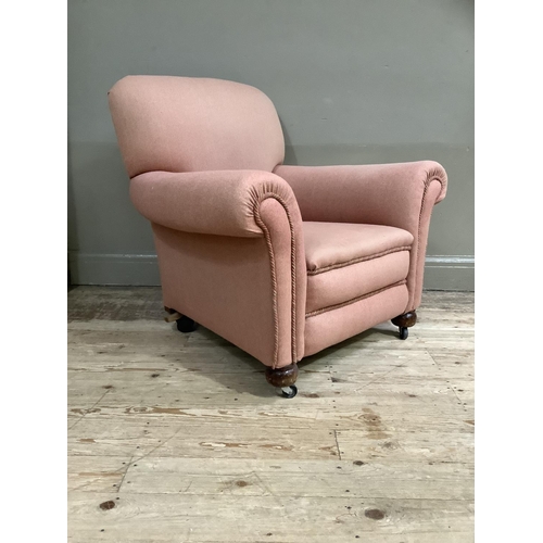 368 - An upholstered armchair in pale coral on compressed bun feet and later casters, circa 1920's