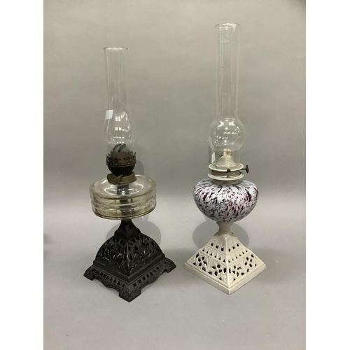 187 - A pair of late Victorian cast iron oil lamps, the first of black metal work with clear glass reservo... 