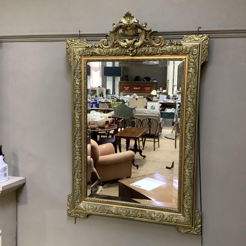 372 - A gilt framed rectangular wall mirror moulded with leaf curls having a pierced foliate cresting and ... 