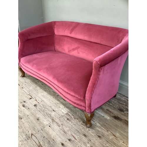 190 - An Edwardian two seater sofa with serpentine seat rail upholstered in pink velvet on short cabriole ... 