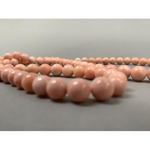 382 - A coral necklace of spherical beads fastened with a drum snap pierced with Chinese characters in yel... 