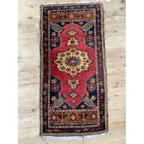 450 - A small prayer rug, the black field with red medallion and further camel coloured medallion enclosin... 