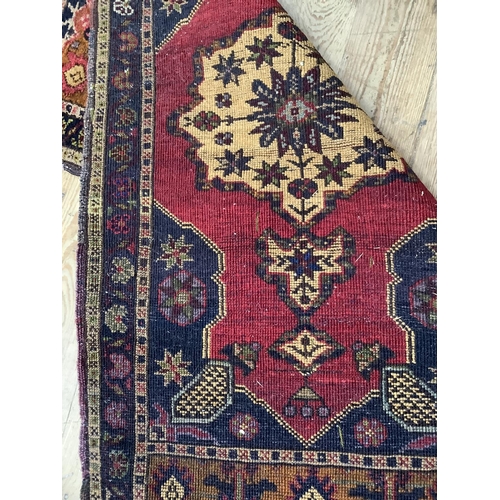 450 - A small prayer rug, the black field with red medallion and further camel coloured medallion enclosin... 