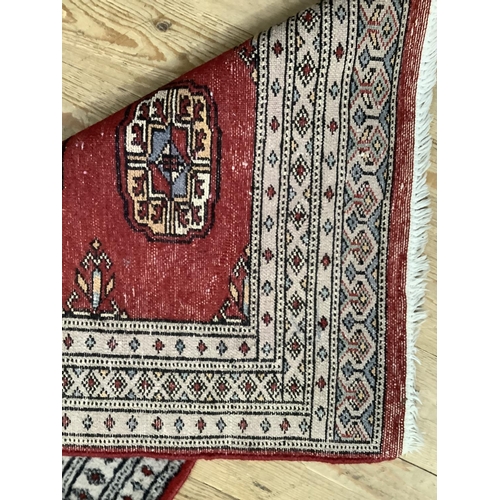 451 - A modern Bokhara rug having a red ground with four medallions within three pale grey borders and end... 