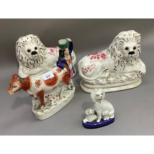 217 - A pair of Staffordshire pottery lions with inset eyes; a cow, calf and farm boy group and a spaniel ... 