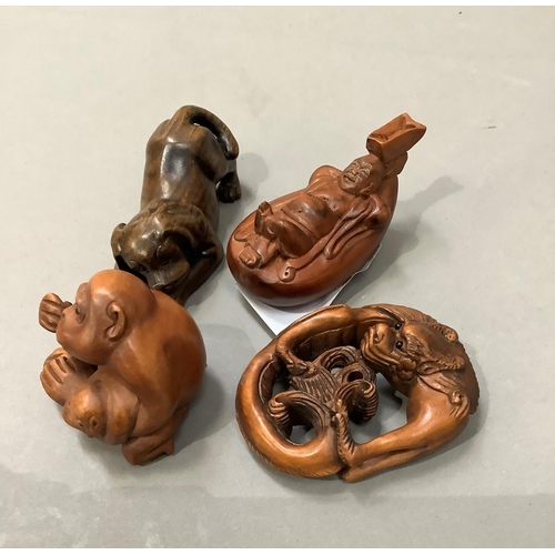 52 - Four carved wood netsukes including monkey and young, dog, a figure relaxing in a boat and a mythica... 