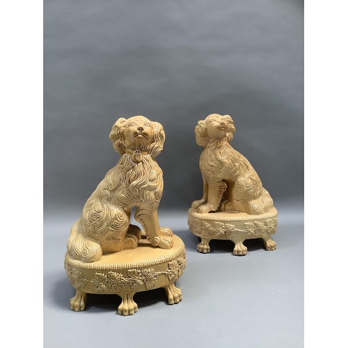 67 - A pair of reproduction Staffordshire style spaniels, seated on an oval base, bordered with stiff lea... 