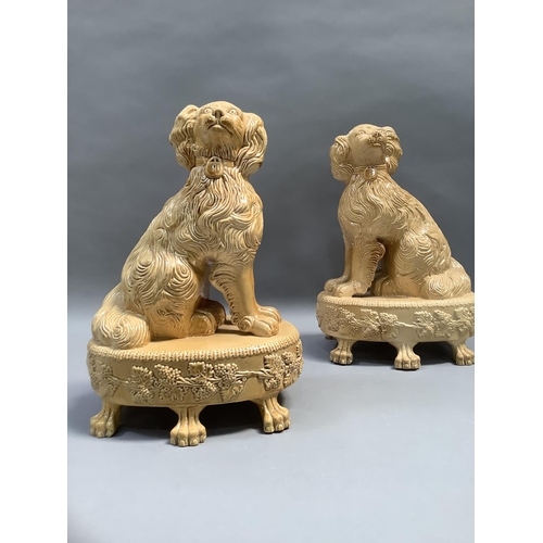 67 - A pair of reproduction Staffordshire style spaniels, seated on an oval base, bordered with stiff lea... 