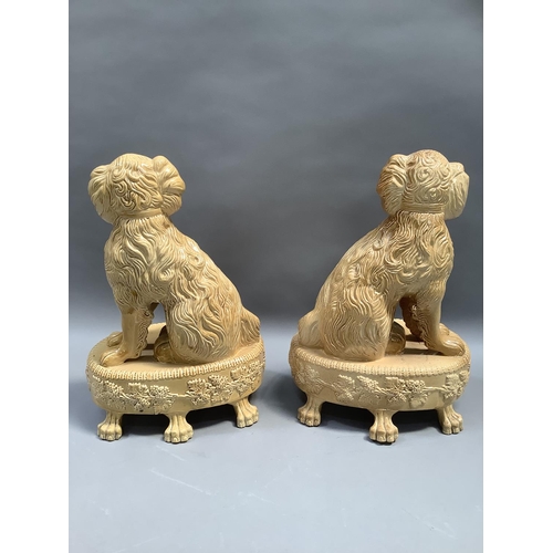 67 - A pair of reproduction Staffordshire style spaniels, seated on an oval base, bordered with stiff lea... 