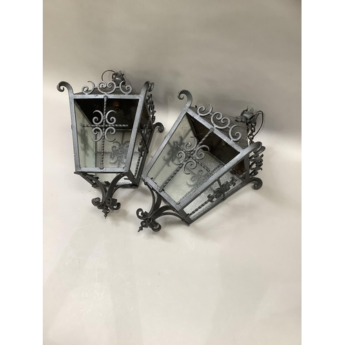 146 - A pair of black wrought iron lanterns with scroll pediment and frame, two panes of glass missing fro... 