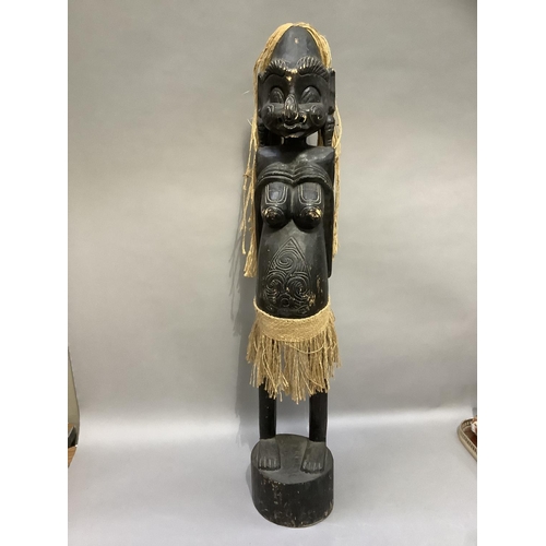 309 - A carved African fertility figure of a female with string hair and skirt, standing on an oval integr... 