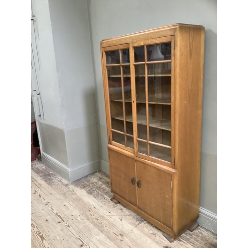 406 - A 1930s walnut and glazed two door bookcase with two door cupboard below on short feet, 81cm wide x ... 