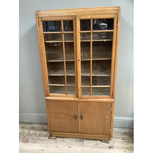 406 - A 1930s walnut and glazed two door bookcase with two door cupboard below on short feet, 81cm wide x ... 